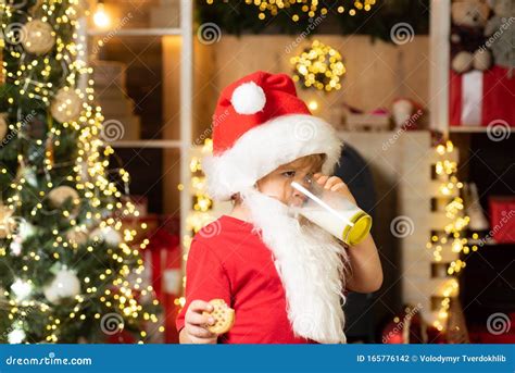 Happy Santa Claus Cute Boy Child Eating A Cookie And Drinking Glass