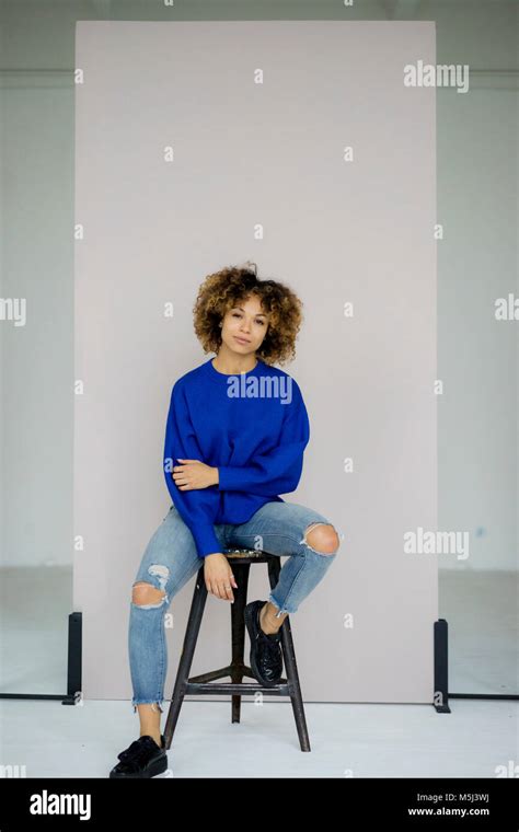 Portrait Of Serious Woman Wearing Blue Pullover Sitting On Stool Stock Photo Alamy