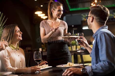 Camarera Sirviendo Comida A Un Grupo De Amigos En El Restaurante Foto