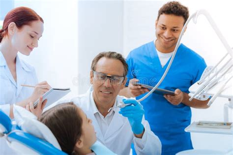 Delighted Positive Doctor Treating His Young Patient Stock Photo