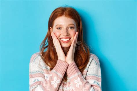 Close Up Of Cheerful Redhead Girl Blushing Touching Cheeks And Smiling Happy Looking Delighted