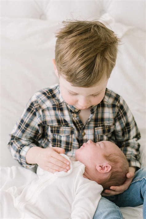 Big Brother Hold Baby Sister For First Time On Bed Stock Photo