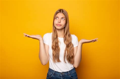 Premium Photo Confused Girl Showing Shrug Gesture And Looking Away Isolated On Yellow