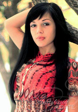 A Woman With Long Black Hair Is Posing For A Photo In Front Of A Tree