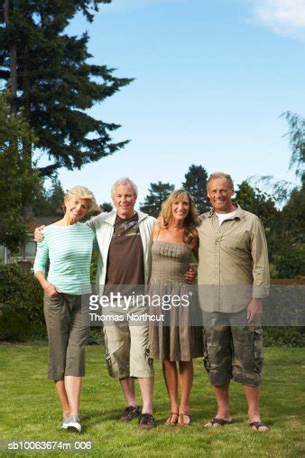 Two Mature Couples Standing In Garden Smiling Portrait High Res Stock