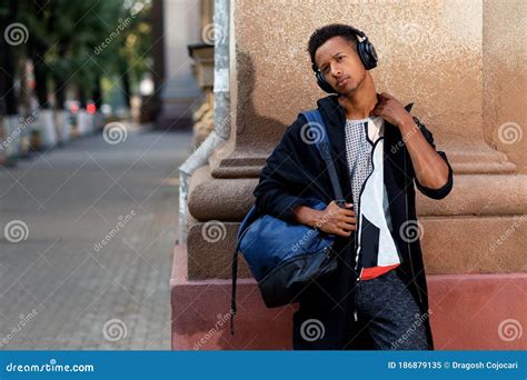 A Man Walking In The Street Listening Music In His Headphones And