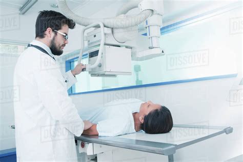 Hispanic Doctor Comforting Patient At X Ray Machine Stock Photo