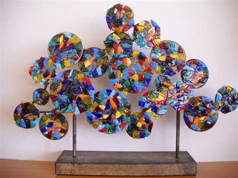 The Sculpture Is Made Up Of Many Different Colored Glass Pieces And Stands On A Wooden Base