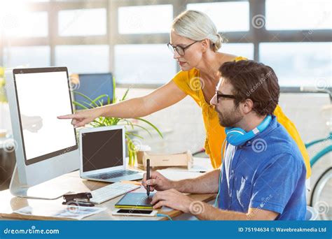 Graphic Designers Interacting While Working On Computer Stock Photo