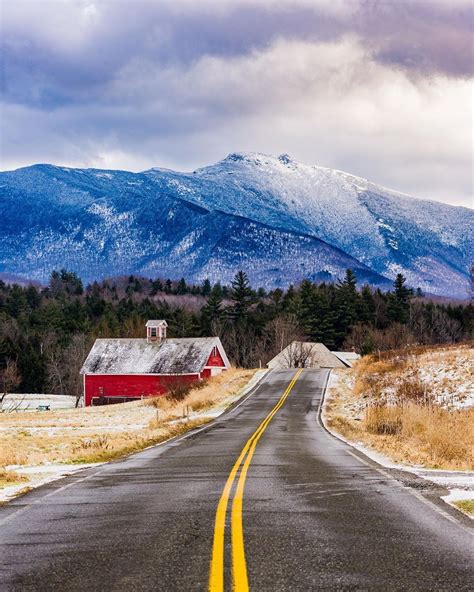 Road In Vermont During Winter With A Red Farmhouse Barn And Snow