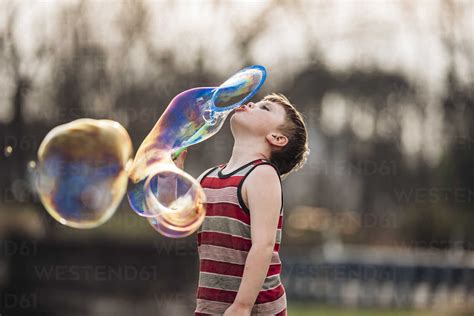 Boy Blowing Bubbles While Playing At Park Stock Photo