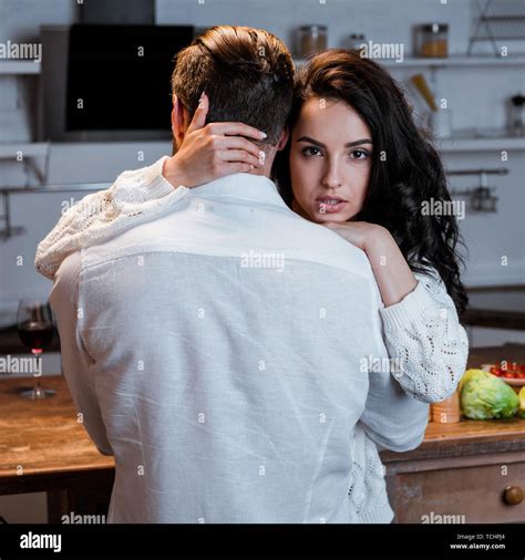 Passionate Brunette Woman Embracing Man And Looking At Camera Stock