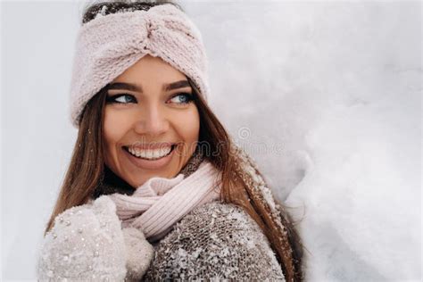 A Girl In A Sweater And Mittens In Winter Stands On A Snow Covered