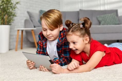 Cute Brother And Sister With Tablet Lying On Floor At Home Stock Image