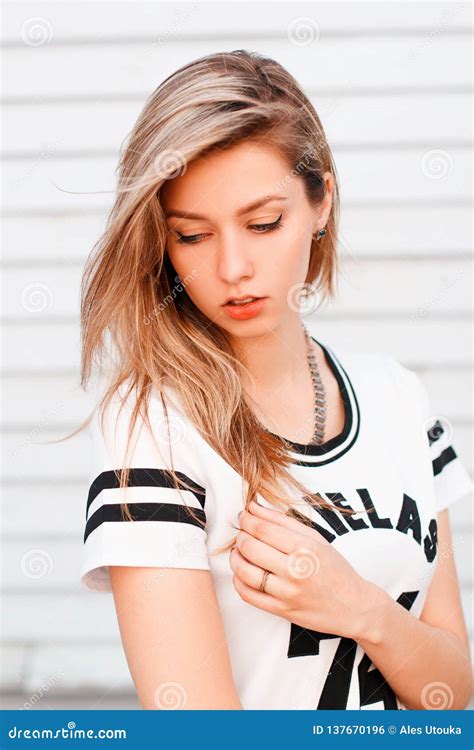 American Girl With Blonde Hair In A Fashionable White T Shirt With A