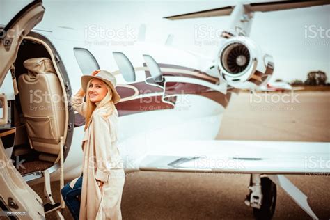 Young Rich Woman Entering A Parked Private Airplane And Smiling While