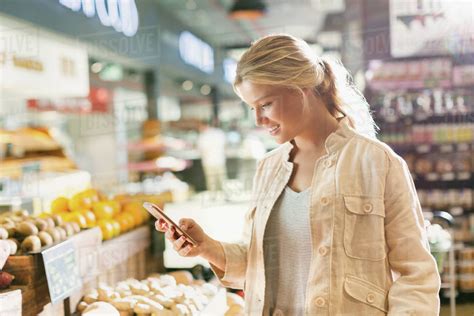 Young Woman Using Cell Phone In Grocery Store Market Stock Photo