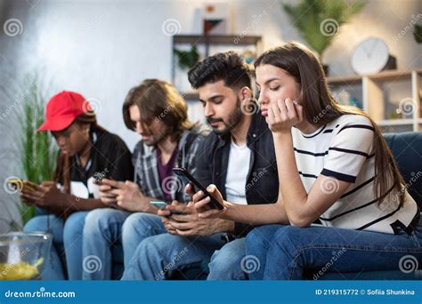 Diverse Friends Using Gadgets While Sitting Together On Sofa Stock