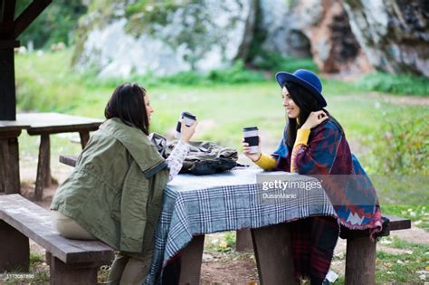 Pretty Young Two Women Sitting Outdoors In Park Drinking Coffee High