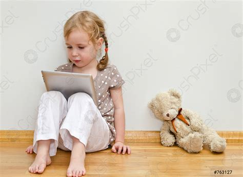 Cute Little Girl Sitting On The Floor Against The Wall Stock Photo