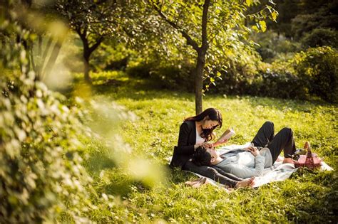 Two People Sitting In The Grass On A Blanket