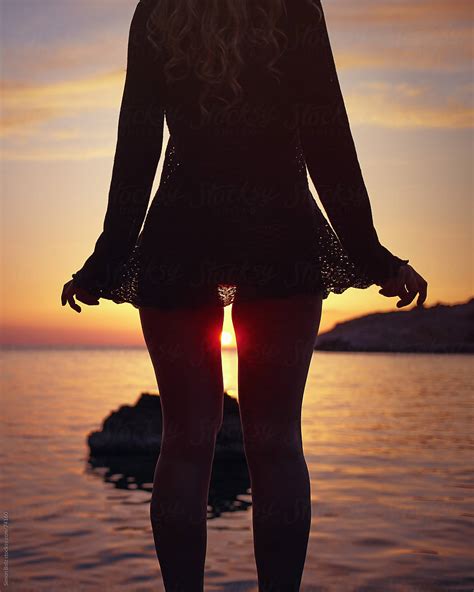 Sun Sets Between Legs Of Woman In Beachwear By Simon Bolz Stocksy United
