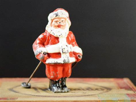 A Santa Clause Figurine Holding A Golf Club On Top Of A Wooden Box