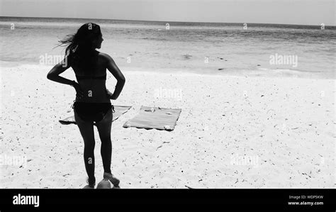 Girl On Beach Wearing Bikini Hands On Hips Rear View Stock Photo