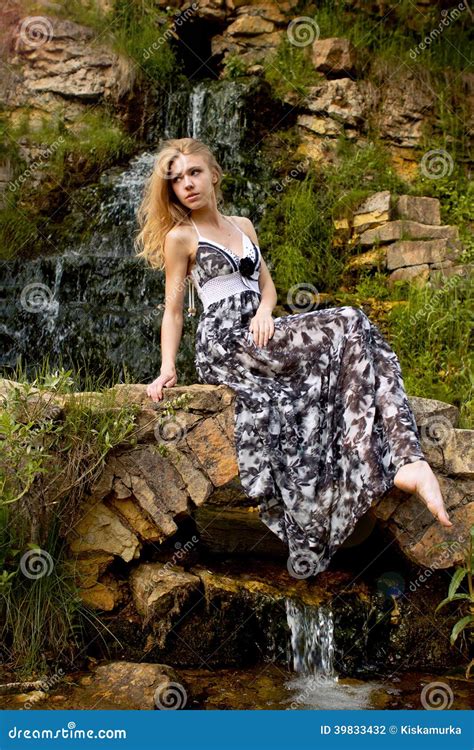 Beautiful Blonde Girl On The Background Of The Waterfall Stock Photo