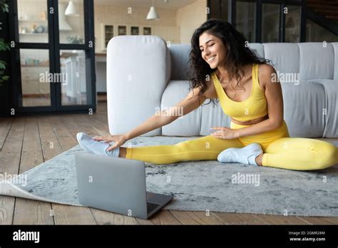 Athletic Caucasian Woman Doing Fitness Exercises On Floor Stretching Her Legs Following Online