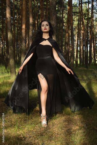 Beautiful Brunette Woman In Black Dress And Black Cloak In The M