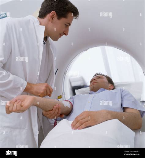 Male Doctor Giving Injection To Patient On MRI Scanbed Stock Photo