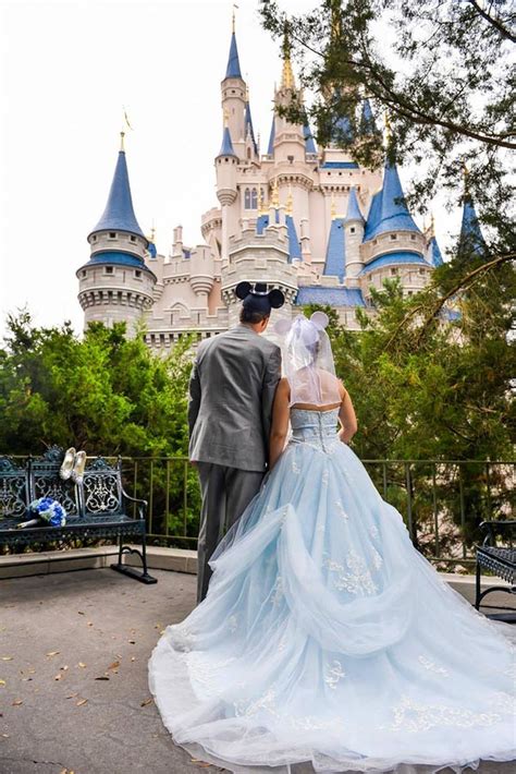 A Bride And Groom Are Standing In Front Of The Sleeping Beauty Castle