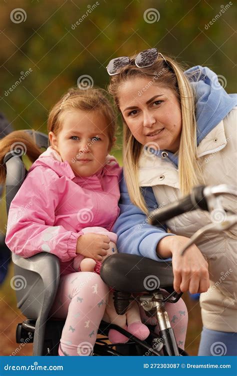 Young Blonde Mother With Long Hair And Red Lips Holding Daughter In