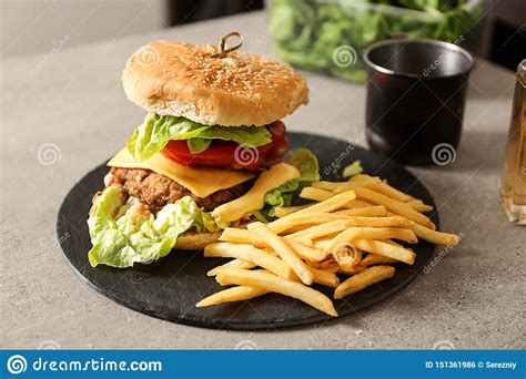 Slate Plate With Tasty Burger And French Fries On Table Stock Photo