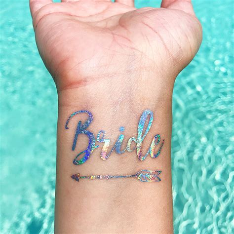 A Womans Wrist With The Word Bride Written On It And An Arrow Tattoo