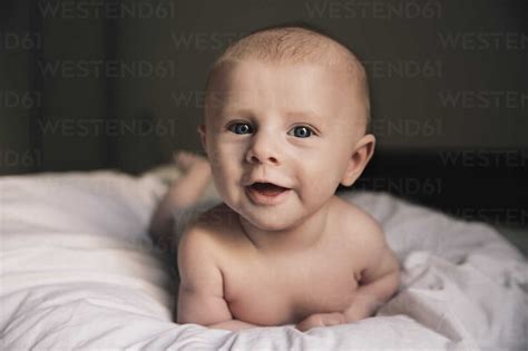 Portrait Of Laughing Baby Boy Lying On Bed Stock Photo