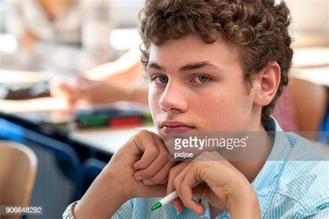 Portrait Head And Shoulders Shot Of A Teenage Boy Sitting At Desk In