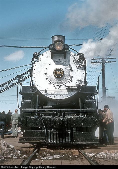 An Old Train Engine With Steam Pouring Out Of Its Chimney And Some