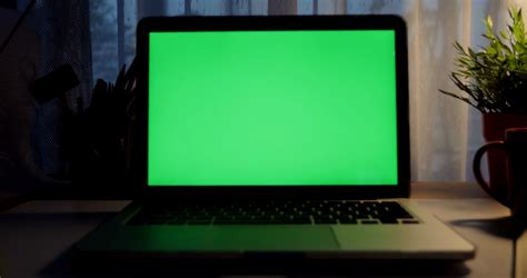 Laptop with green screen. Dark office. Dolly out. Perfect to put your ...