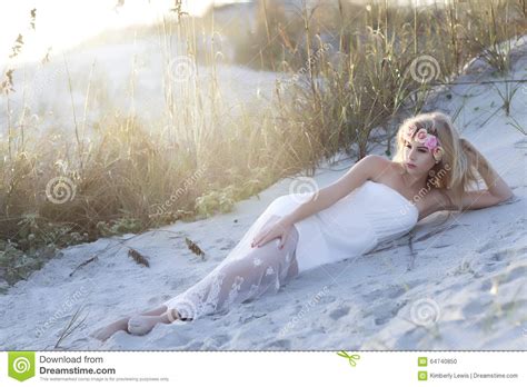 A Tall Blond Woman Laying In The Sand With Floral Wreath