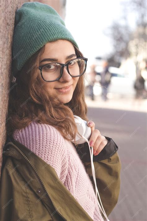 Premium Photo Cute Hipster Girl In Glasses And Hat Smiling Stands On A City Street Fashion