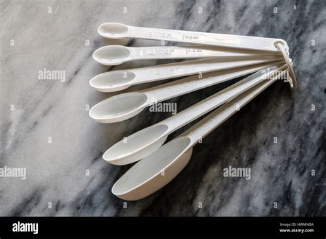 Set Of White Plastic Measuring Spoons Showing Imperial And Metric
