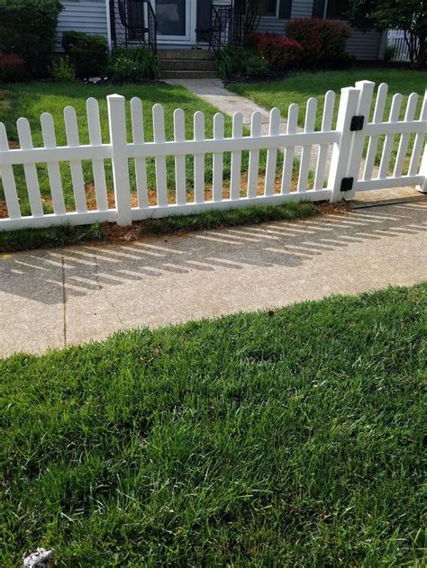 A White Picket Fence Sitting On Top Of A Lush Green Field Next To A