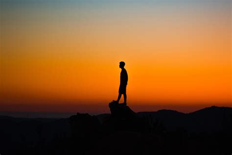 silhouette of man on top of rock formation hd wallpaper wallpaper flare