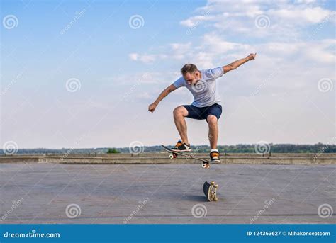 Young Skateboarder Performing A Flip Trick In A Jump On The Road The
