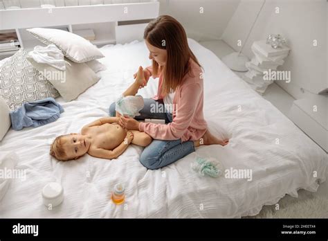 Happy Mother Changing Diaper To Her Baby In Bedroom Stock Photo Alamy
