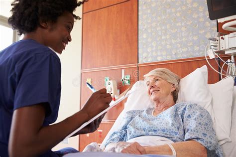 Nurse Talking To Senior Female Patient In Hospital Bed Stock Image