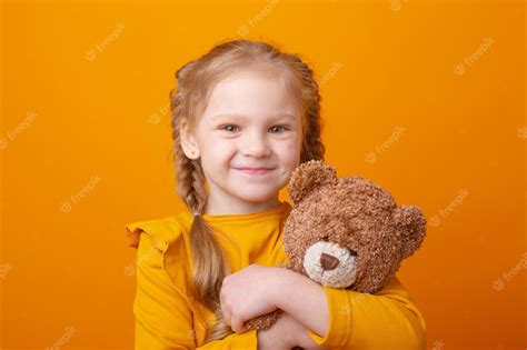 Premium Photo Cute Little Girl Holding A Teddy Bear On A Yellow