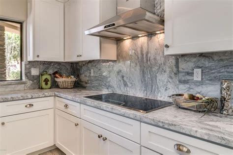 Las vegas renovation features dayton white kitchen cabinets with glass inserts and cool gray painted harbor lower cabinets. Kitchen with arabescus white marble counter with gray ...
